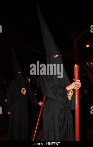 Eine vermummte Büßer, die mit einer Kerze während der Semana Santa in Malaga, Spanien Stockfoto