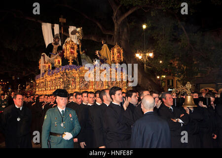 Eine christliche Bruderschaft, die mit einem Schwimmer während der Karwoche (Semana Santa) in Malaga, Spanien Stockfoto