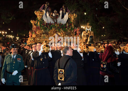 Eine christliche Bruderschaft, die mit einem Schwimmer während der Karwoche (Semana Santa) in Malaga, Spanien Stockfoto