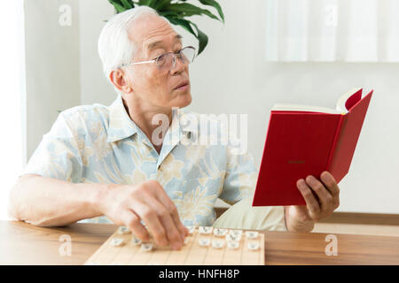 Ein senior Mann spielt ein Shogi-problem Stockfoto