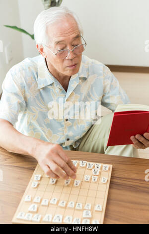 Ein senior Mann spielt ein Shogi-problem Stockfoto