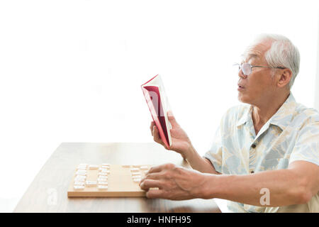 Ein senior Mann spielt ein Shogi-problem Stockfoto