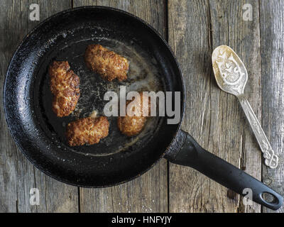 Zubereitung von Schnitzel. 12. Februar 2017. Pfanne mit gebratenen Koteletts auf einem alten verwitterten Holztisch Credit: Igor Golovniov/ZUMA Draht/Alamy Live News Stockfoto