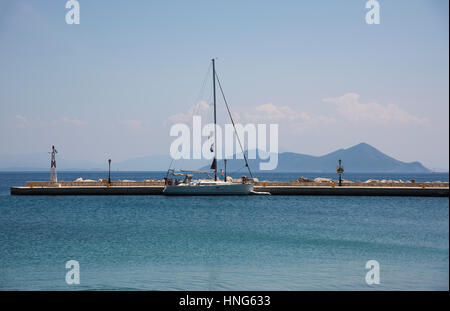 Blick über Pier und Segeln boa in Frikes Hafen auf der Insel Ithaka in Griechenland, mit der Insel Atokos im Hintergrund Stockfoto