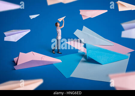 Kreative Surrealismus Design mit Origami Papierflieger. Junges Mädchen lassen Papierflieger. Blau, blau, rosa Origami basteln. Stockfoto