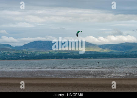 Ein Kitesurfer Newborough Strand mit Snowdonia im Hintergrund Stockfoto
