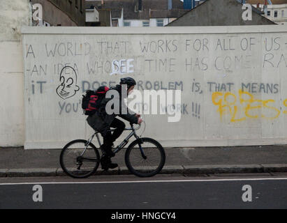 Radfahren über politische Graffiti in Brighton Stockfoto