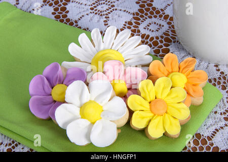 Schickes elegantes hausgemachte Frühlingsblumen Zucker Cookies mit königlicher Zuckerglasur Blütenblätter verrohrt auf serviert auf einer grünen Serviette auf Tisch mit weißer Spitze Tischdecke ein Stockfoto