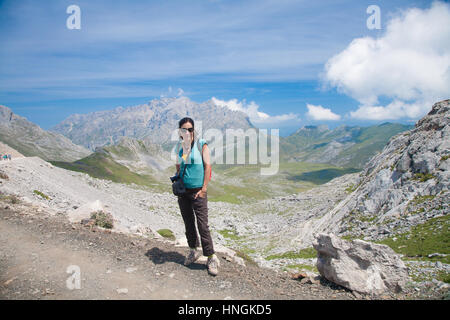 Brünette Sport wandern oder trekking Frau mit grünen Hemd braun Hose posiert mit Blick auf Tal und Berg im Naturpark der Picos de Europa in Dose Stockfoto