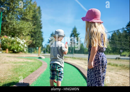 Zwei kleine Kinder, Mini-Golf oder Crazy Golf spielen im eine Minigolf-Anlage im Sommer Stockfoto