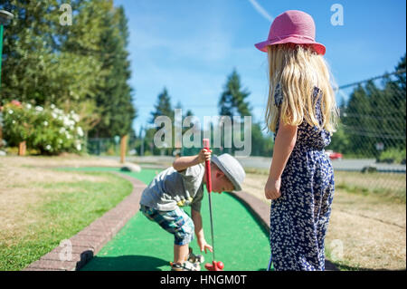 Zwei kleine Kinder, Mini-Golf oder Crazy Golf spielen im eine Minigolf-Anlage im Sommer Stockfoto