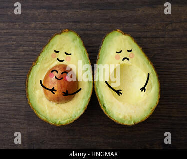 Eine Avocado Elternteil und Kind in Umarmung neben einem anderen Avocado, das ist traurig, dass es ohne ein Kind oder baby Stockfoto