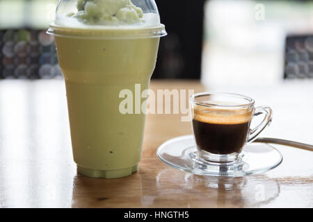 Tasse Espresso Shot und Matcha Grüntee Frappe Smoothie auf Holztisch Stockfoto