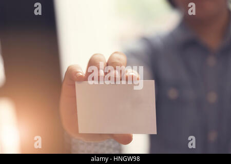 Frau Hand mit leeren weißen Namenskarte, Tiefenschärfe und Vintage-Ton Stockfoto