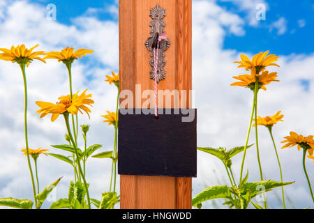 kleine Tafel hängen Schlüssel vor einem Feld mit gelben Blumen Stockfoto