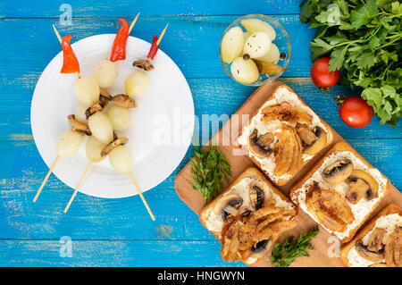 Knusprig getoastetem Weißbrot in der Form eines Quadrats mit Pilzen, Zwiebeln, Pommes frites, Sauce Tartar auf ein Schneidebrett und kleine eingelegte Zwiebeln Stockfoto