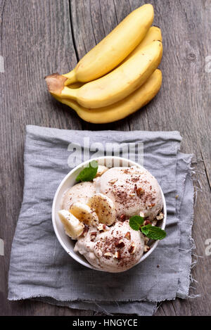 Fruchteis aus Bananen und Nüssen auf hölzernen Hintergrund, Ansicht von oben Stockfoto