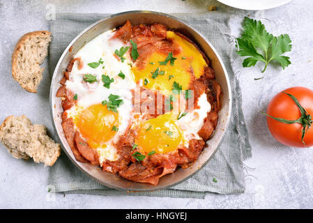 Spiegeleier mit Tomaten und Speck in Pfanne, Ansicht von oben, Nahaufnahme Stockfoto