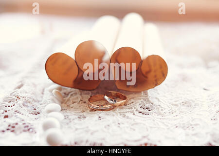 Gold Trauringe Braut und Bräutigam auf dem Hintergrund der Herzen Stockfoto