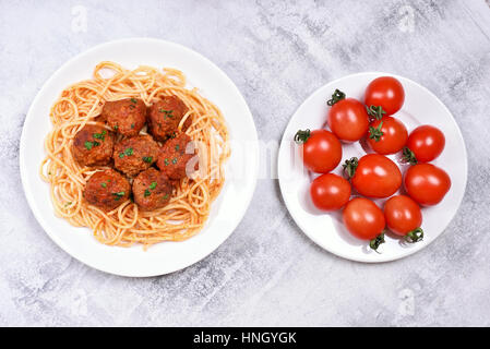 Spaghetti mit Fleischbällchen und Teller mit frischen Tomaten, Ansicht von oben Stockfoto