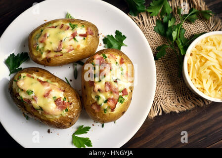 Köstliche Kartoffelschalen mit Speck, Käse und grüne Zwiebel, Ansicht von oben Stockfoto