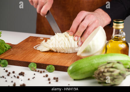 Nahaufnahme des Küchenchefs Hände schneiden Kohl auf einem Holzbrett Stockfoto