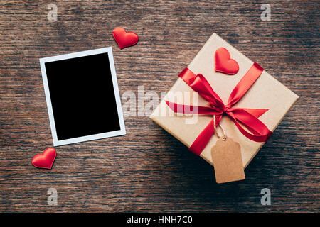 Leere Foto Frame und Geschenk-Box mit roten Herz auf Holz Hintergrund. Stockfoto