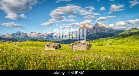 Idyllische Berglandschaft der Dolomiten mit traditionellen alten Chalets und Wiesen im schönen Abendlicht bei Sonnenuntergang, Alpe di Siusi, Italien Stockfoto