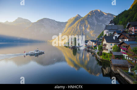 Klassische Panorama der Stadt berühmte Hallstatt am See in den Alpen mit traditionellen Passagier Schiff im schönen frühen Morgenlicht in der Morgendämmerung, Österreich Stockfoto