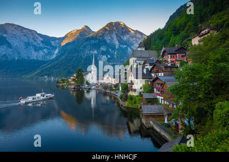 Klassische Postkartenblick auf berühmte Hallstätter See Stadt in den Alpen mit traditionellen Passagier Schiff im schönen frühen Morgenlicht in der Morgendämmerung, Österreich Stockfoto