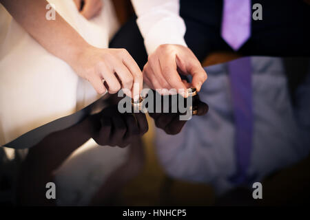 Die Braut und der Bräutigam nehmen Trauringe von der Spiegelfläche Stockfoto
