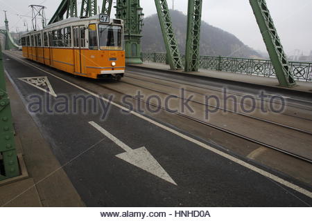 Eine gelbe Straßenbahn kreuzt an einem nebeligen Tag Freiheitsbrücke in Budapest, Ungarn. Stockfoto