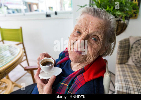 Senior alte türkische Frau lächelt in die Kamera und türkischer Kaffee trinken Stockfoto