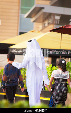 Dubai, Vereinigte Arabische Emirate - 23. Oktober 2016. Mann in traditioneller Kleidung, Wandern mit Kindern. Stockfoto