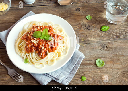 Spaghetti Bolognese Nudeln mit Tomatensauce und Hackfleisch / Faschiertes, geriebenem Parmesan und frischem Basilikum - gesunde italienische Pasta aus Eigenproduktion auf rustikal aus Holz Stockfoto