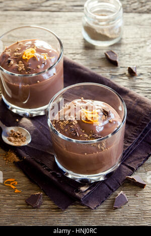 Schokoladenmousse garniert mit Orange Zest in Gläsern über hölzerne Hintergrund schließen sich - köstliche hausgemachte Schokoladenpudding Stockfoto