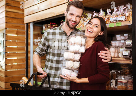 Fröhliche junge Paar tun, Einkaufs- und Marshmalows im Lebensmittelgeschäft zu kaufen Stockfoto