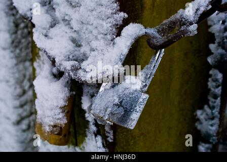 Vorhängeschloss am Zaun in Eis und Schnee bedeckt Stockfoto