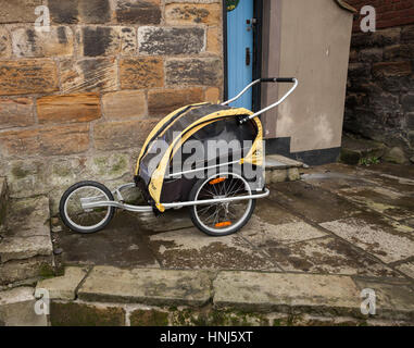 Burley d Kinderwagen parkten außerhalb ein malerisches Steinhaus in Staithes, North Yorkshire, England, UK Stockfoto