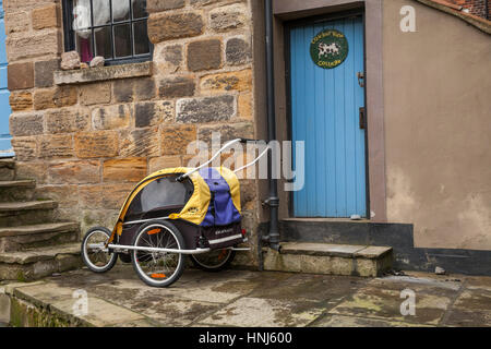 Burley d Kinderwagen parkten außerhalb einer Steinhütte in Staithes, North Yorkshire, England Stockfoto