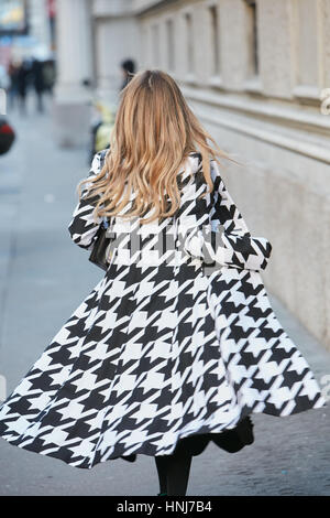 Frau mit schwarzen und weißen pied de Poule Mantel Wandern bevor Salvatore Ferragamo Modenschau, Milan Fashion Week Streetstyle am Januar 2017. Stockfoto