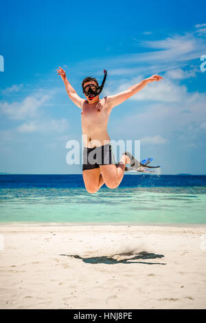 Lustiger Mann springt in Flossen und Maske. Urlaub an einem tropischen Strand auf den Malediven Inseln. Stockfoto