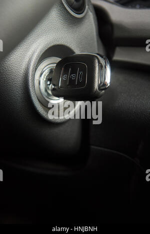 Nahaufnahme von Autoschlüssel im Schlüsselloch für die Zündung. Makroaufnahme einer modernen Start Autoschlüssel vertikale Stockfoto
