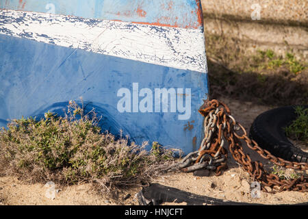 Umgedrehten blauen Rumpf einer Jolle mit rostigen Kette am Strand Stockfoto