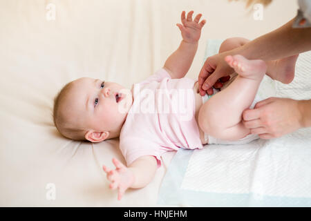 Mutter ändert die Windel ihre kleine Tochter Stockfoto