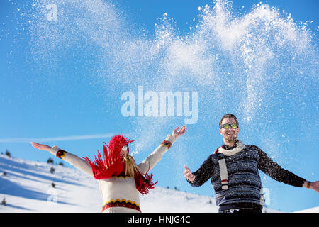 Schneeballschlacht. Winter-Paare, die Spaß im Schnee im Freien spielen. Junge fröhliche multiethnische Brautpaar. Stockfoto