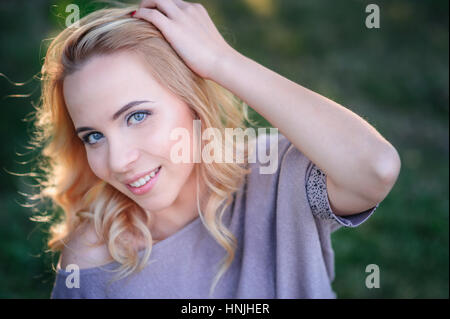 schöne junge Frau mit Make-up posiert in einem Sommerpark Stockfoto