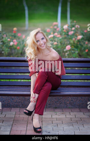 schöne blonde Frau sitzen auf einer Bank im park Stockfoto