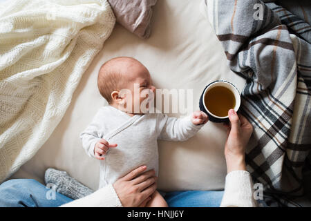 Nicht erkennbare Mutter mit Neugeborenen Sohn auf Bett liegend Stockfoto