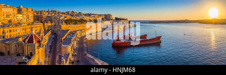 Valletta, Malta - Panorama Skyline Blick auf Valletta und den Grand Harbour mit wunderschönen Sonnenaufgang, Schiffe und klaren, blauen Himmel Stockfoto